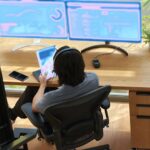 a person sitting at a desk with a computer 1
